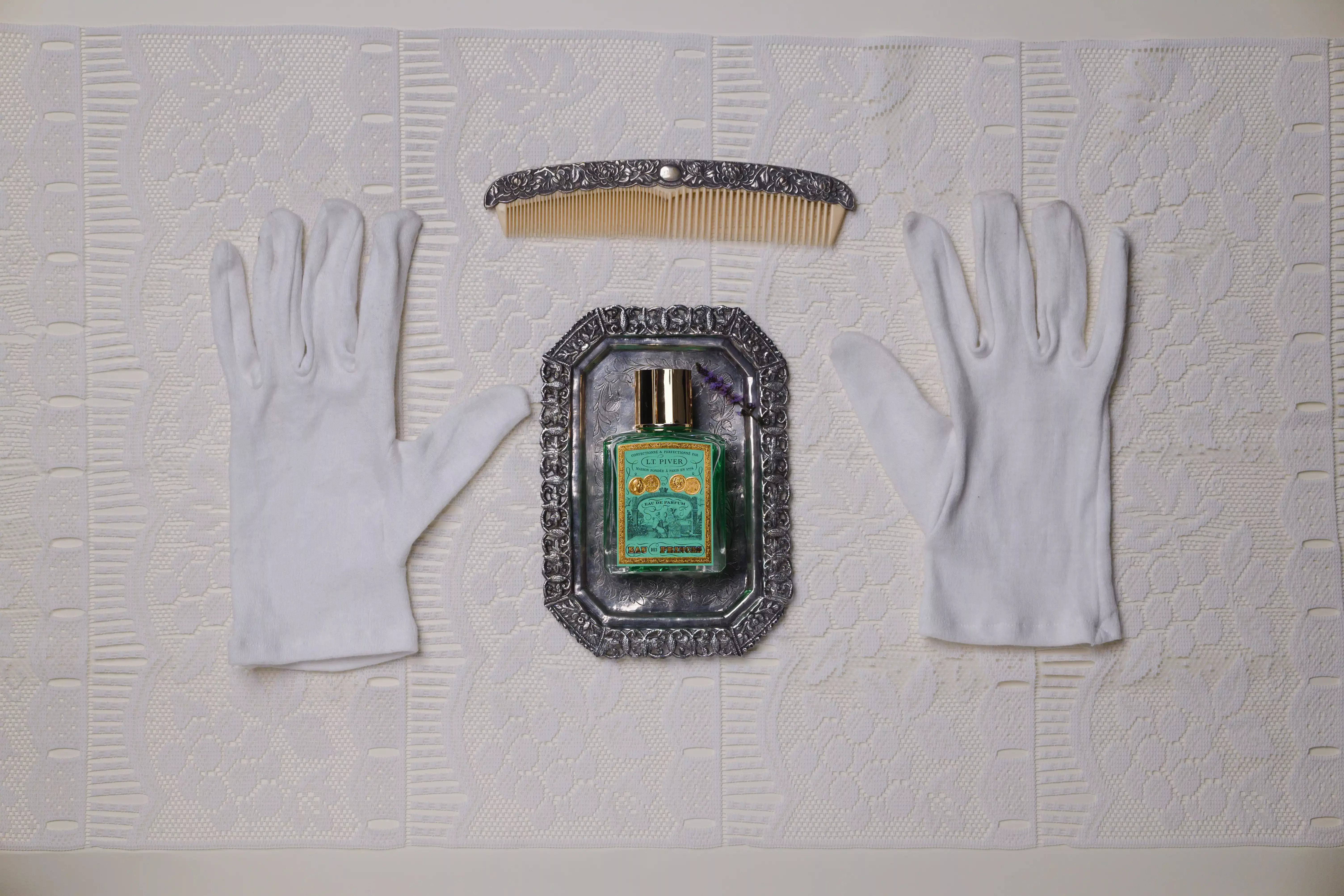 Flacon Eau des Princes de L.T. Piver avec un gant et un diadème pour une ambiance élégante et royale.