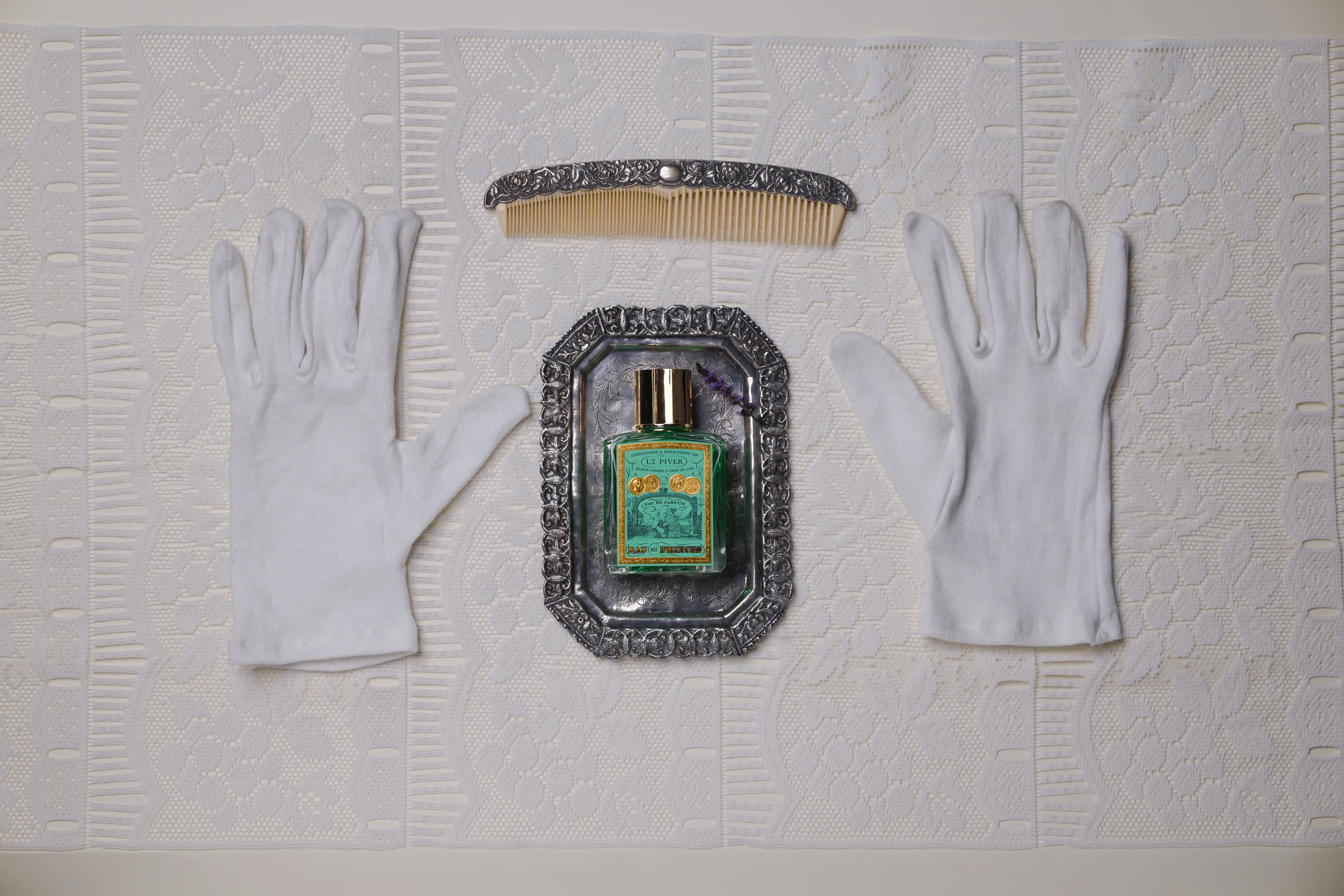 Flacon Eau des Princes de L.T. Piver avec un gant et un diadème pour une ambiance élégante et royale.
