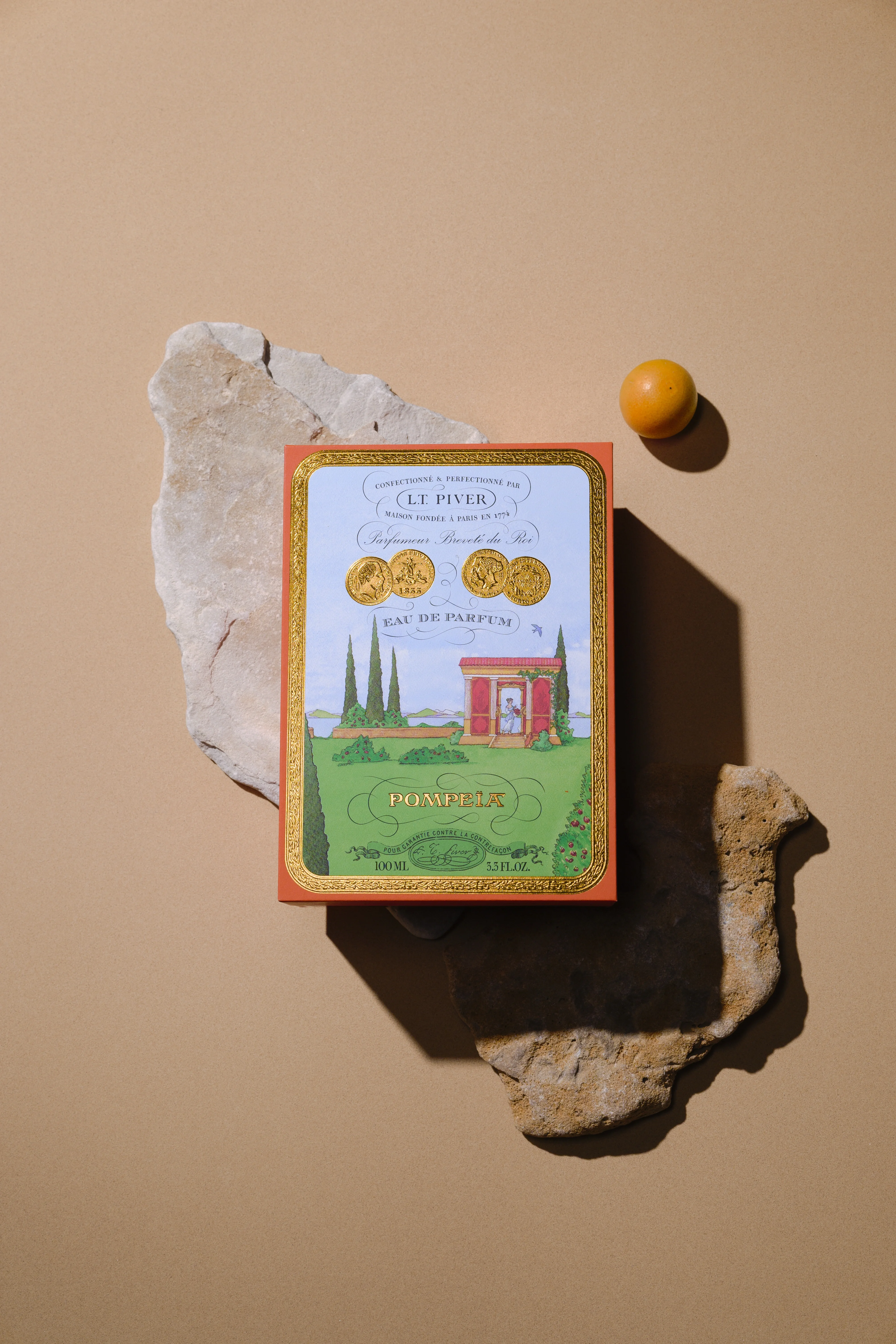 Coffret d’eau de parfum Pompeia de L.T. Piver posé sur un décor minéral évoquant l’héritage antique et l’art du parfum.