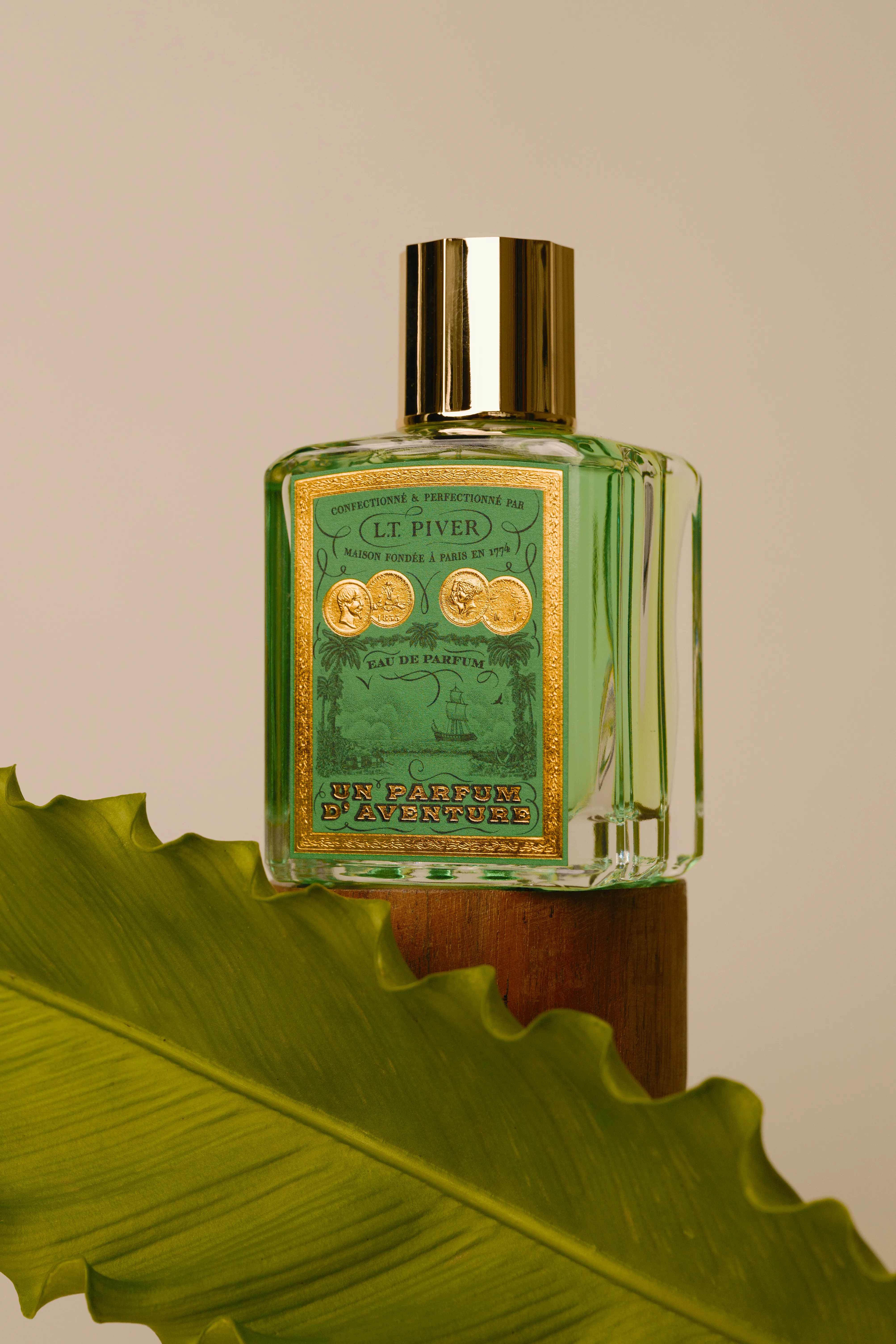 Flacon de parfum vert Un Parfum d’Aventure de L.T. Piver posé sur une feuille végétale